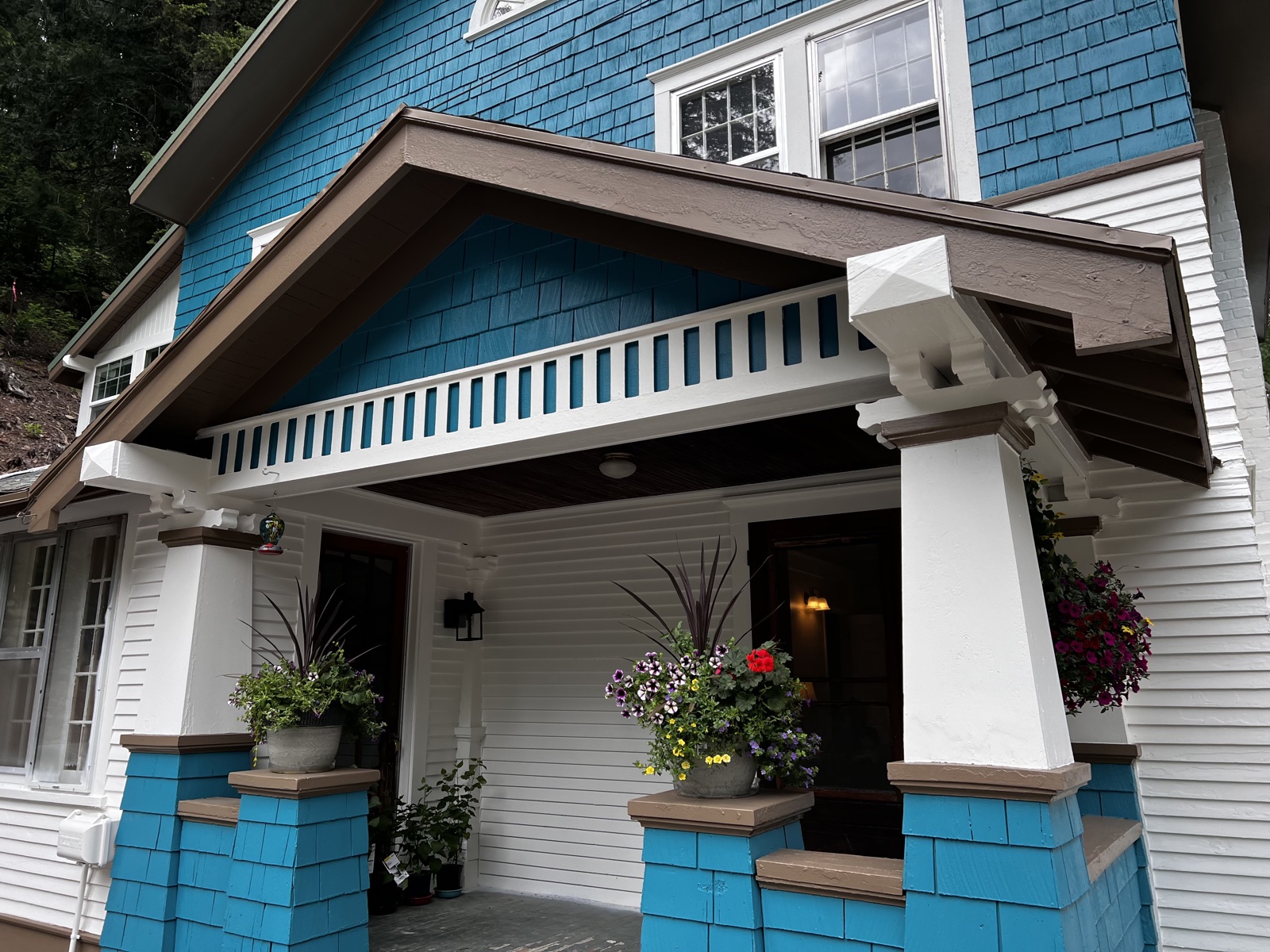 Two-story modern home with bright white siding, dark trim and roofing, fresh exterior paint visible across the upper floors