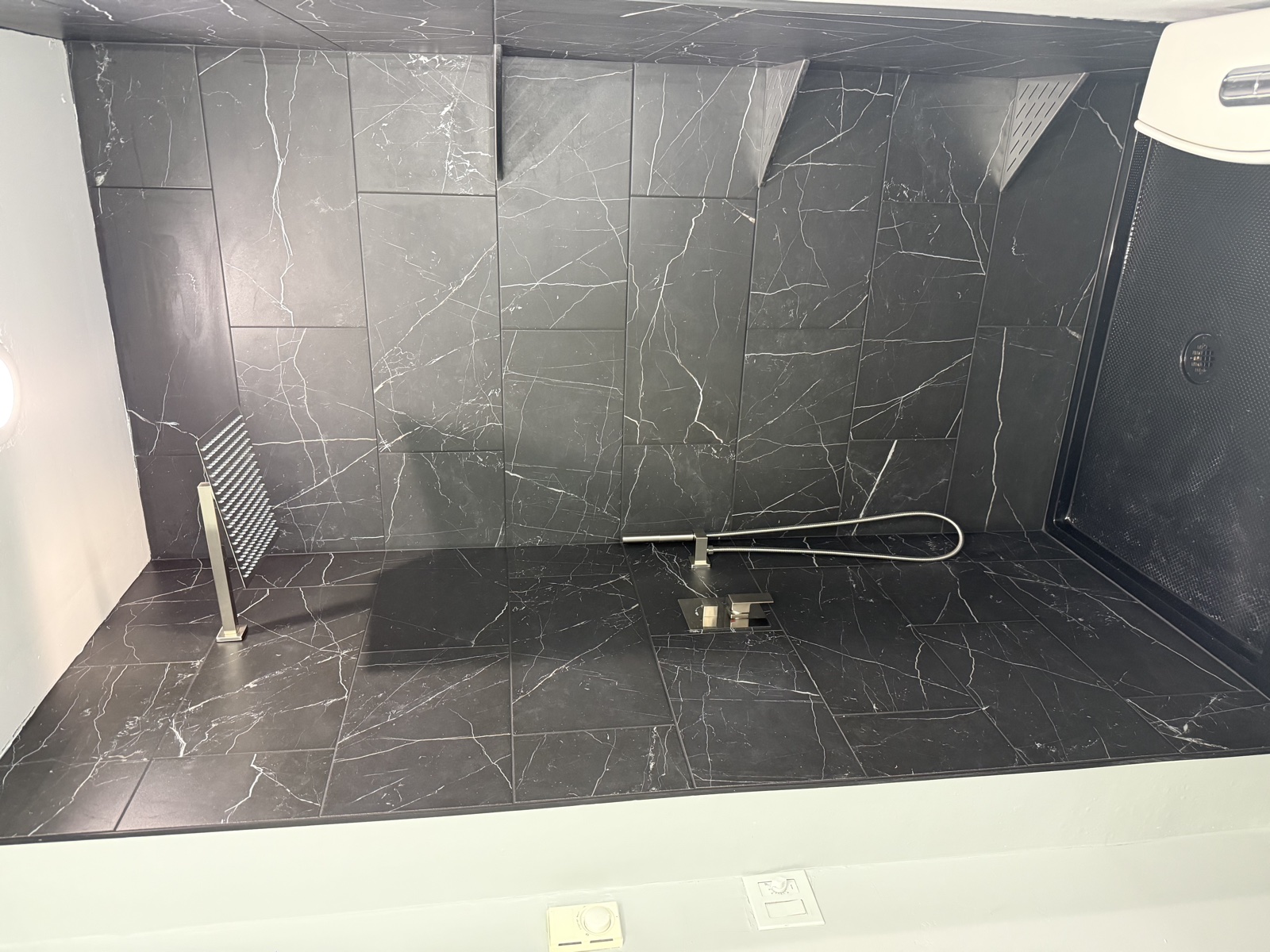 Walk-in shower remodel with floor-to-ceiling marble tile surround, glass shower partition, frosted privacy window, and combined rainshower and handheld fixtures