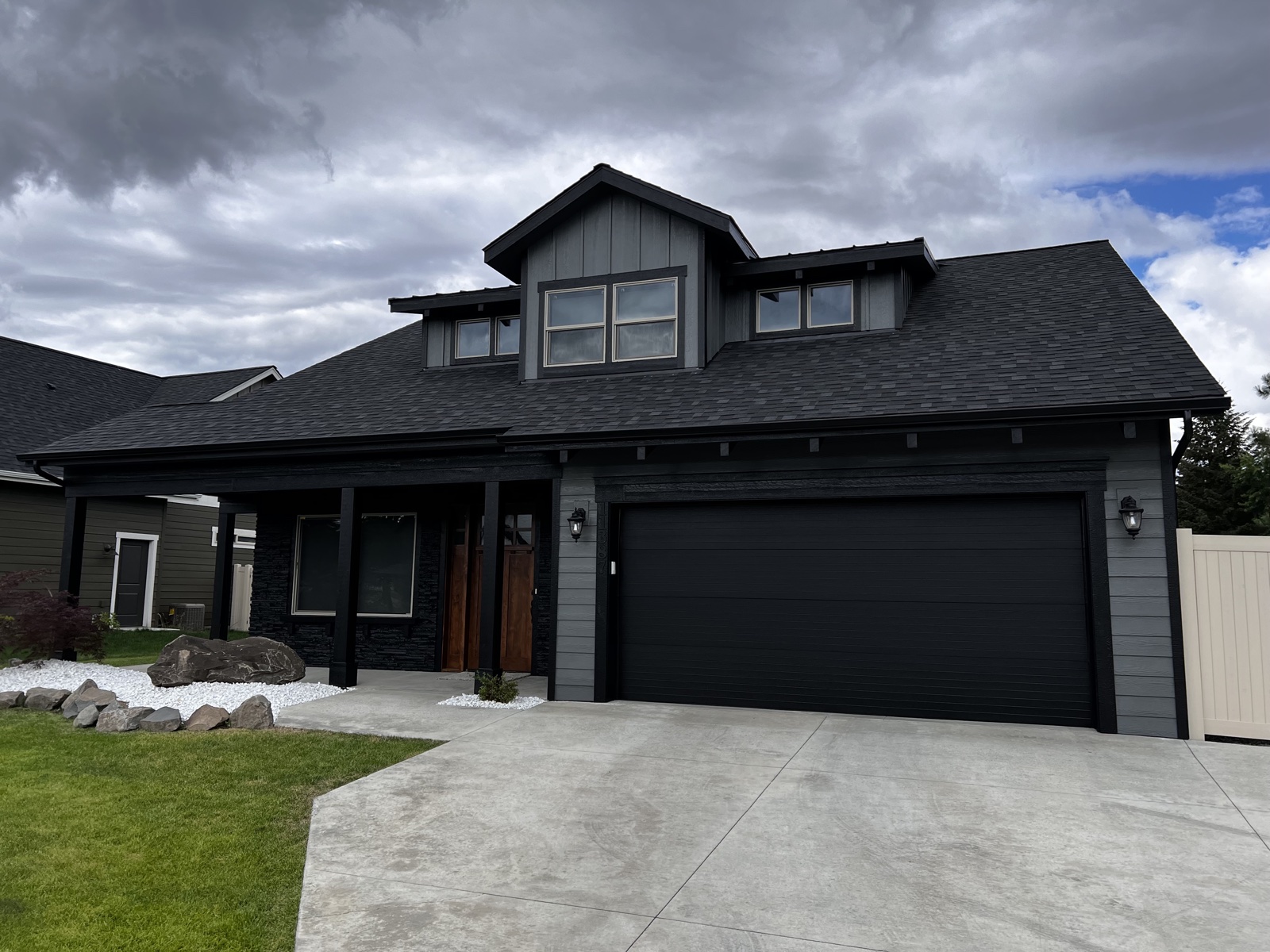 Residential exterior painting — dark craftsman home with black stone accents